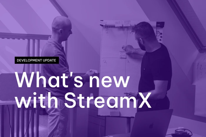 Two men discussing and placing sticky notes on a whiteboard in an office setting, with overlaid text reading 'Development Update: What's new with StreamX'.